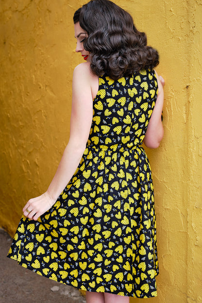 a backshot of a model wearing a honey hives vintage dress leaning against a yellow wall