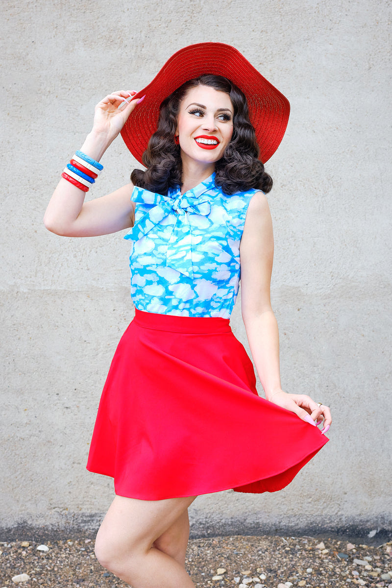 a model standing in front of a wall wearing red skater skirt