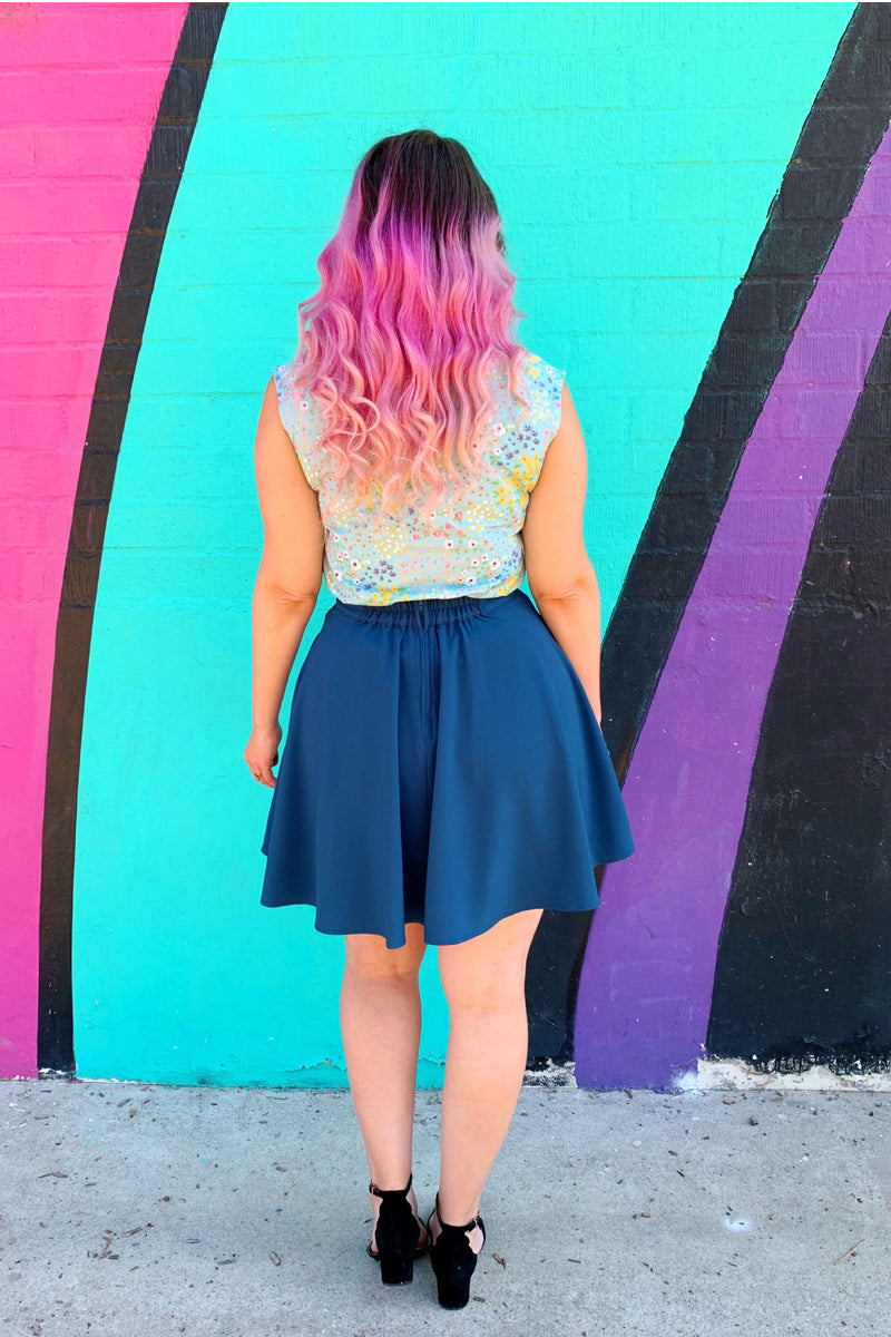 a back view of model standing in front of coloful wall wearing the ocean blue skater skirt