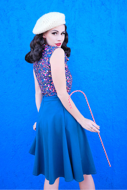 a back view of a model standing in front of a brigth blue wall wearing the charlotte skirt in blue