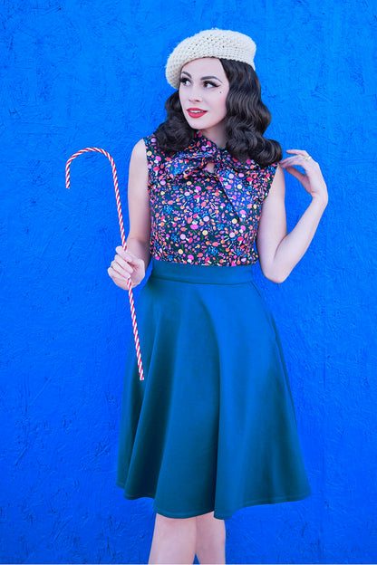 a model standing in front of a brigth blue wall wearing the charlotte skirt in blue