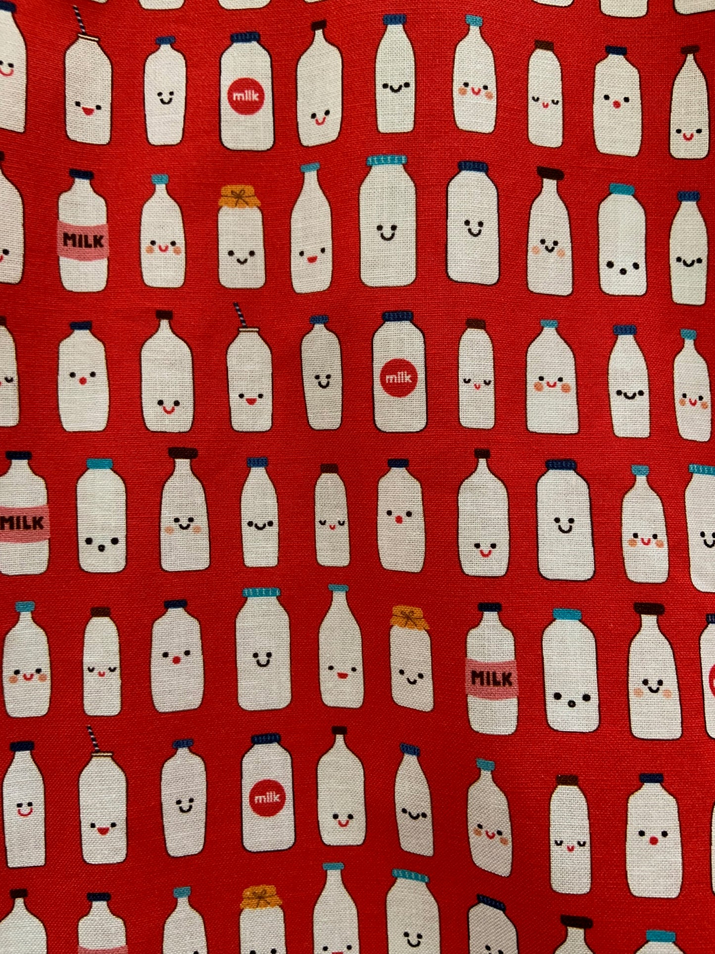 a close up of the fabric of the got milk? skater dress showing cute faces on milk bottles that are lined up on red background