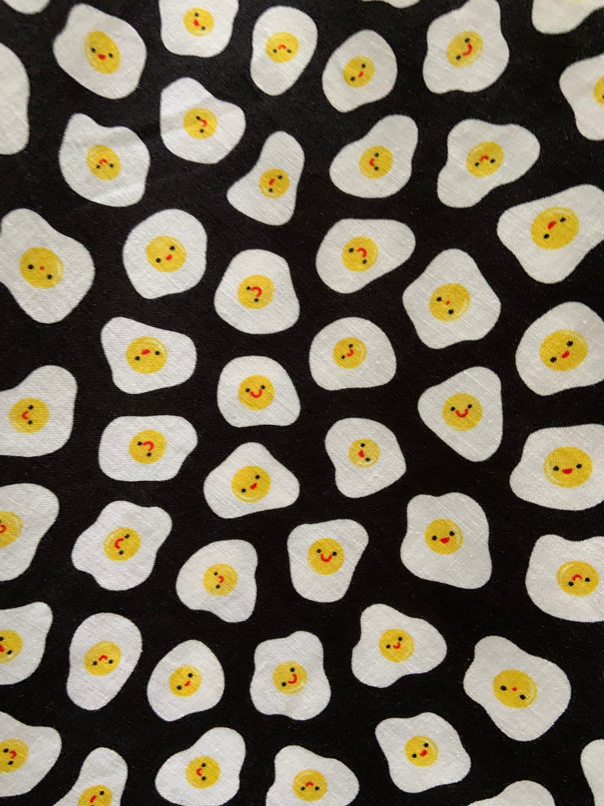 a close up of the fabric showing the smiley faces on the eggs