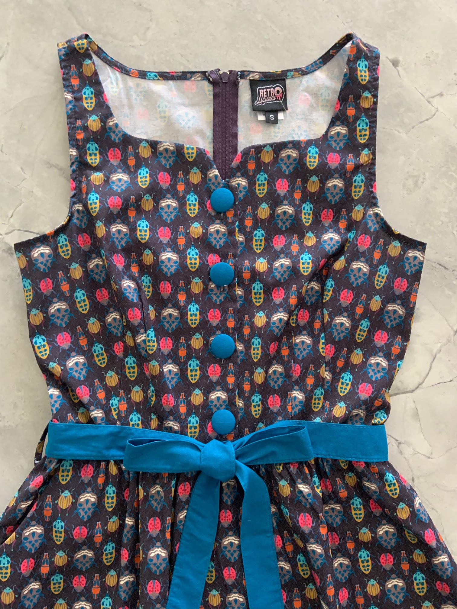 a close up of bodice of insects ida dress showing blue buttons and sash