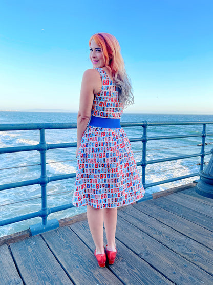a back view of model standing on a boardwalk with the ocean in the backgroun wearing the sunny days fit and flare dress