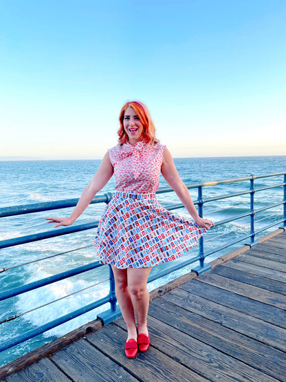 a model standing on boardwalk with the ocean in the background wearing sunny days skater skirt