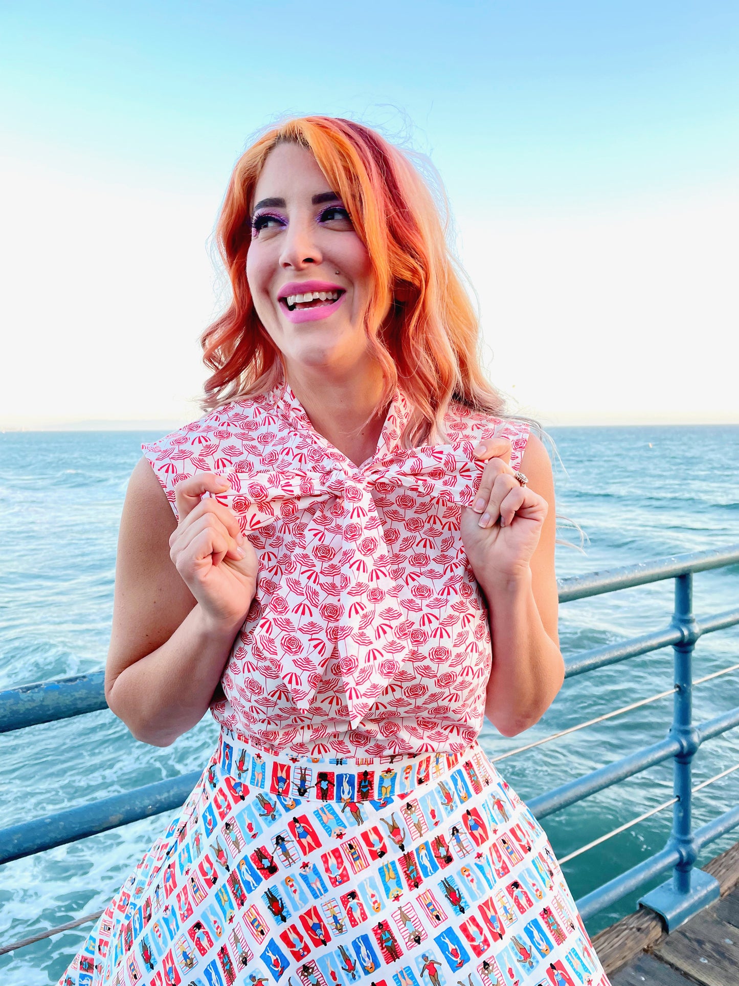 a close up of a model standing on boardwalk with the ocean in the background wearing sunny days skater skirt