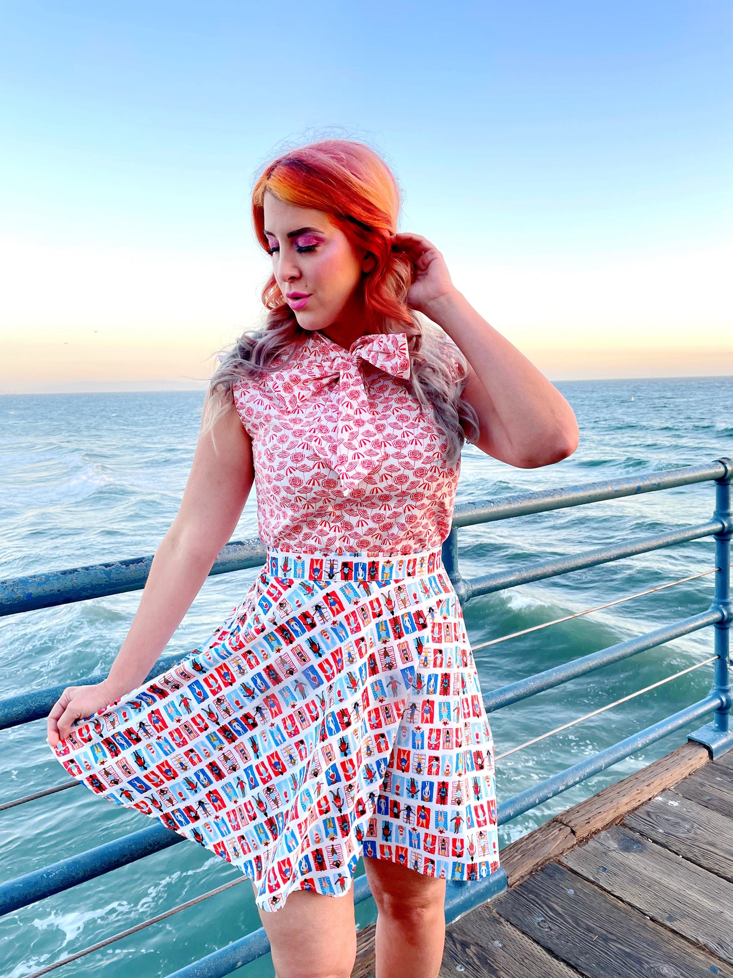 a close up of a model standing on boardwalk with the ocean in the background wearing sunny days skater skirt