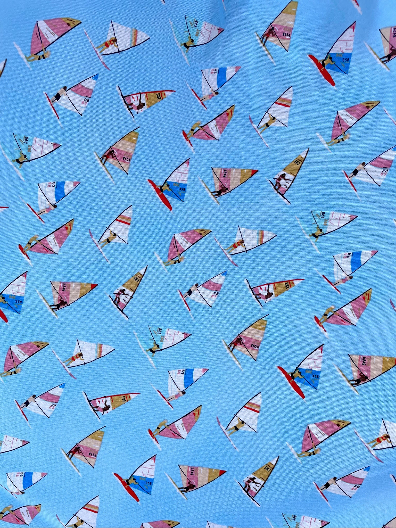 a close up of fabric showing windsurfers on blue background