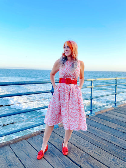 a model standing on the boardwalk in front of the ocean wearing umbrella midi dress