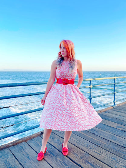 a model standing on the boardwalk in front of the ocean wearing umbrella midi dress