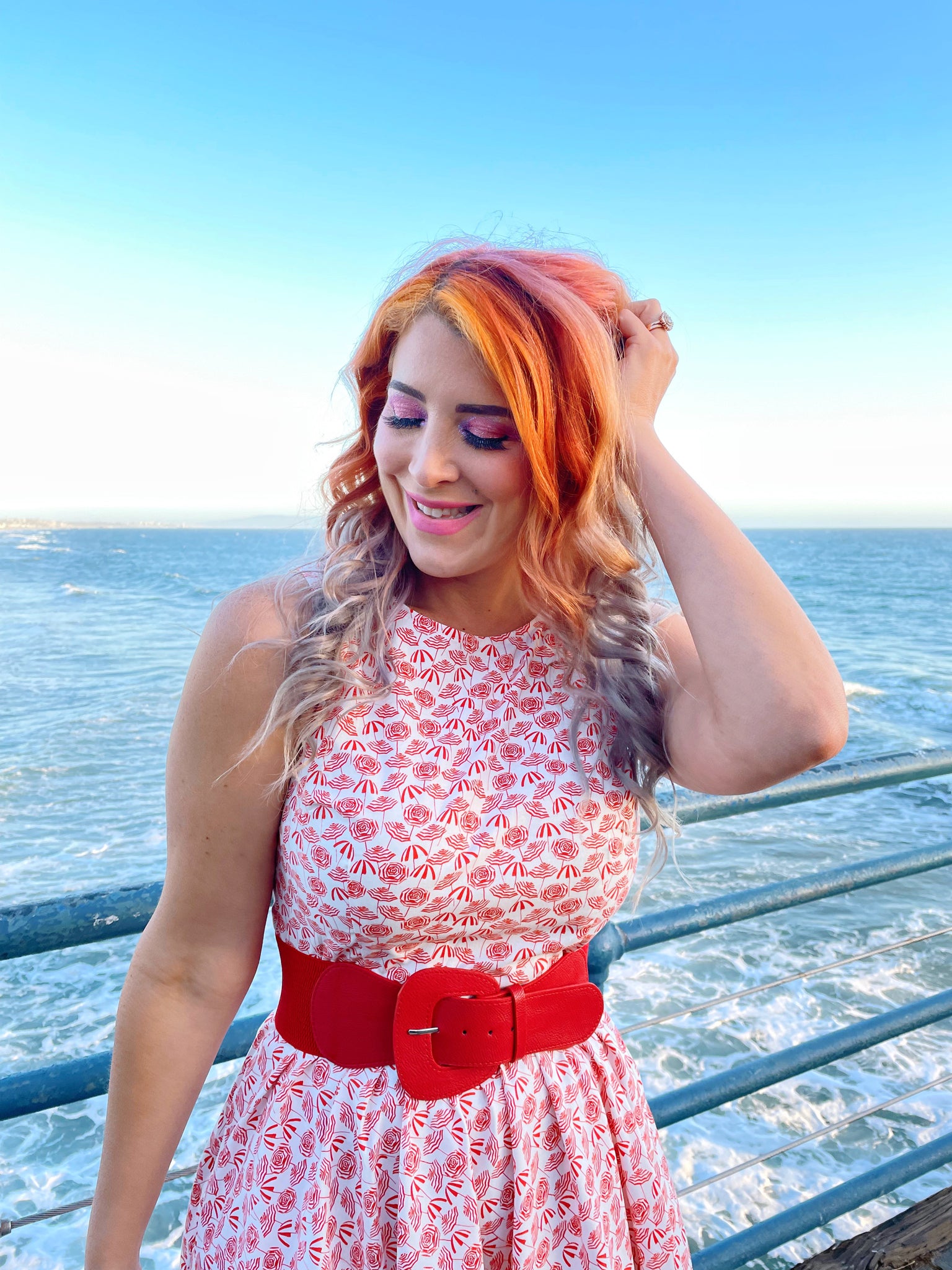 a close up of model standing on the boardwalk in front of the ocean wearing umbrella midi dress