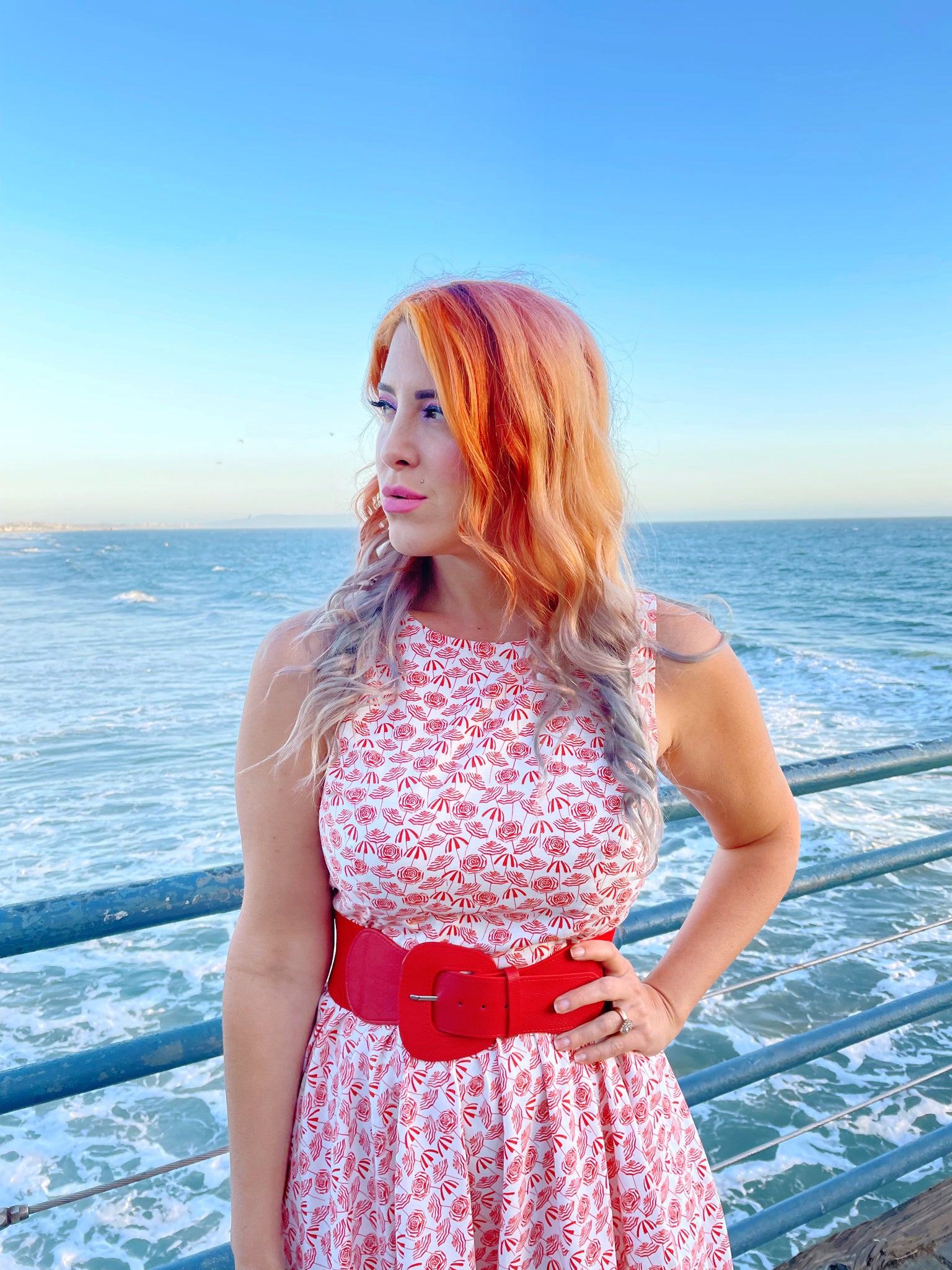 a close up of model standing on the boardwalk in front of the ocean wearing umbrella midi dress