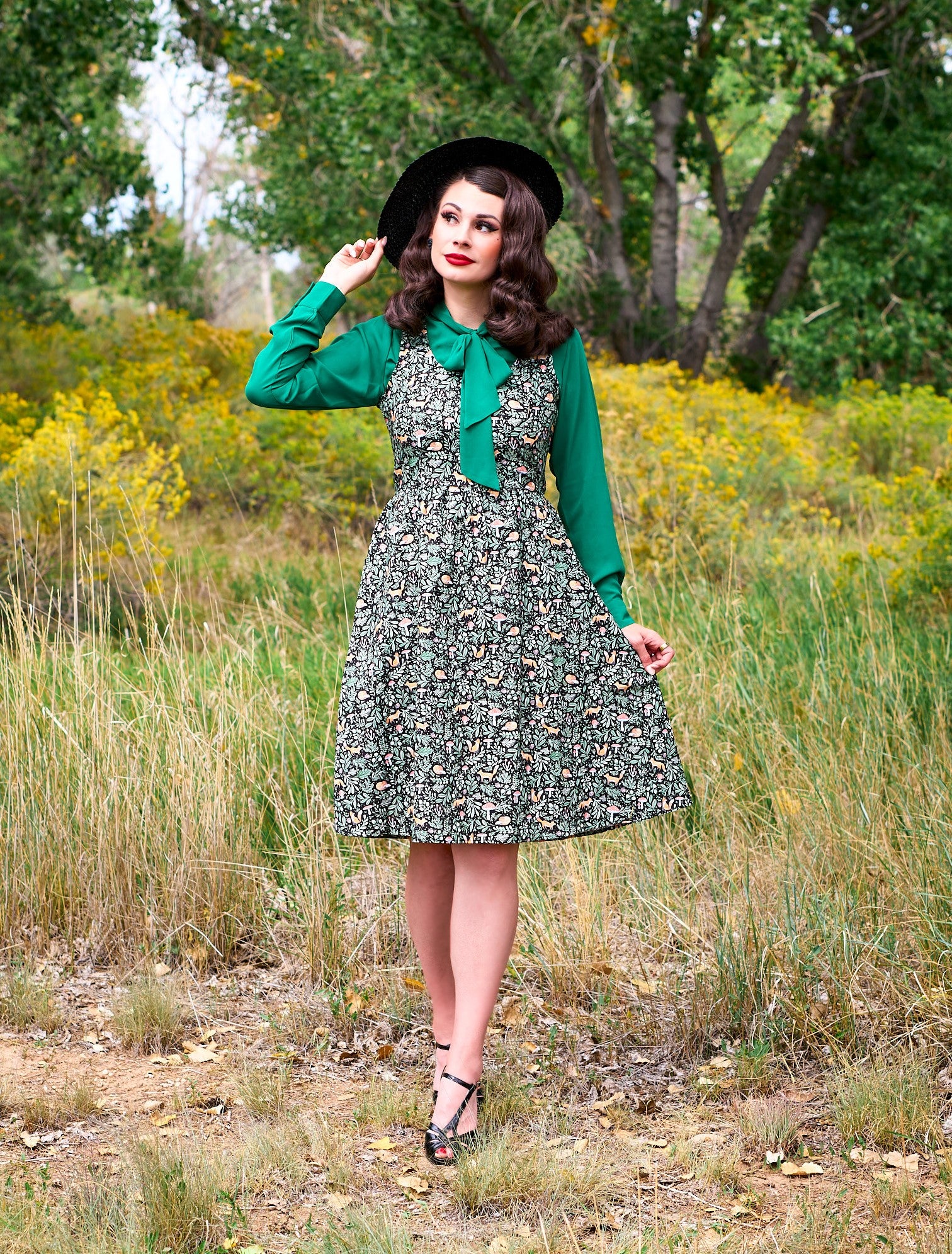 a full size image of a model standing outdoors in front of trees wearing the foxy fit and flare dress