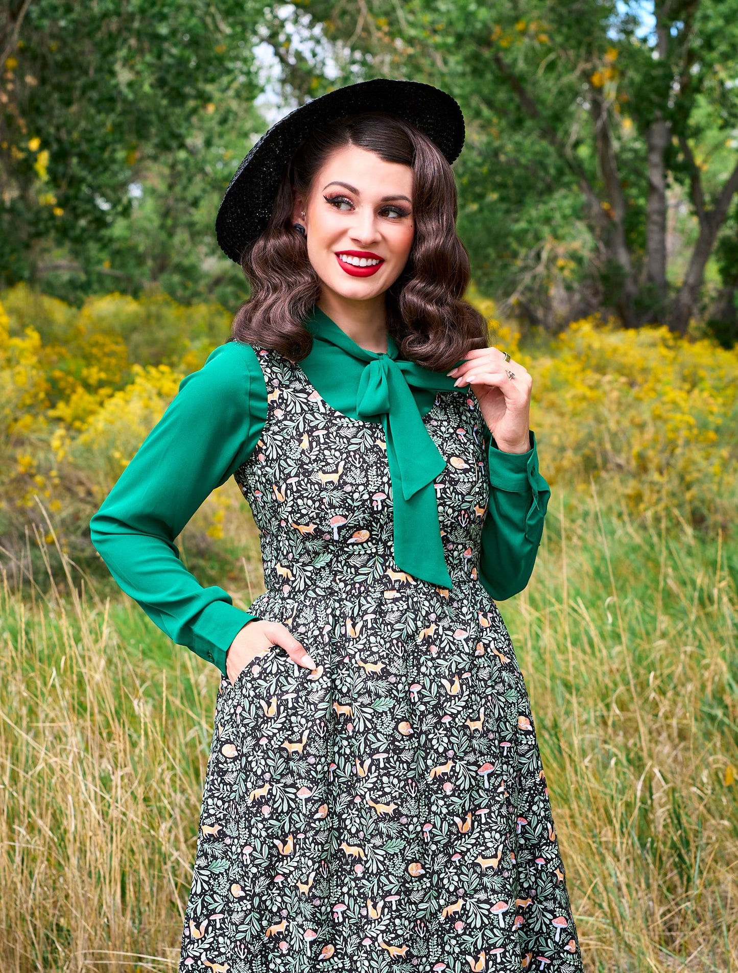 a close up of a model standing in front of trees wearing the helen retro blouse in green