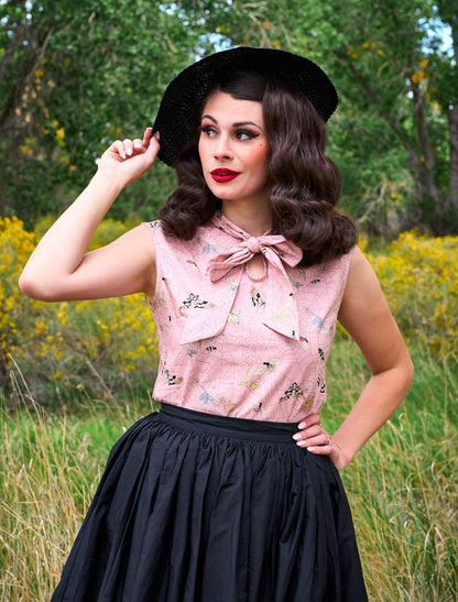 a model wearing our moth bow top looking to the side and her hand is on her hat
