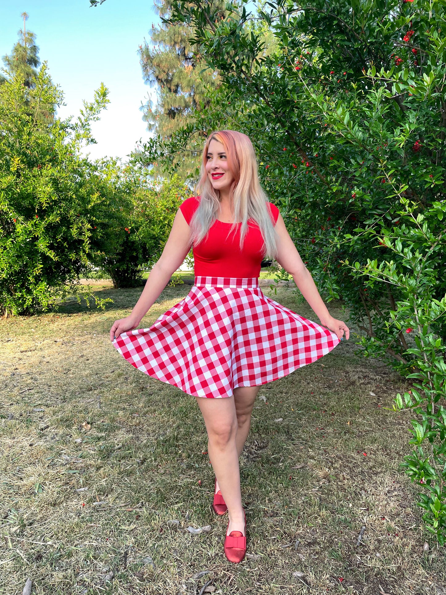 a model outdoors in front of trees wearing red gingham skater skirt