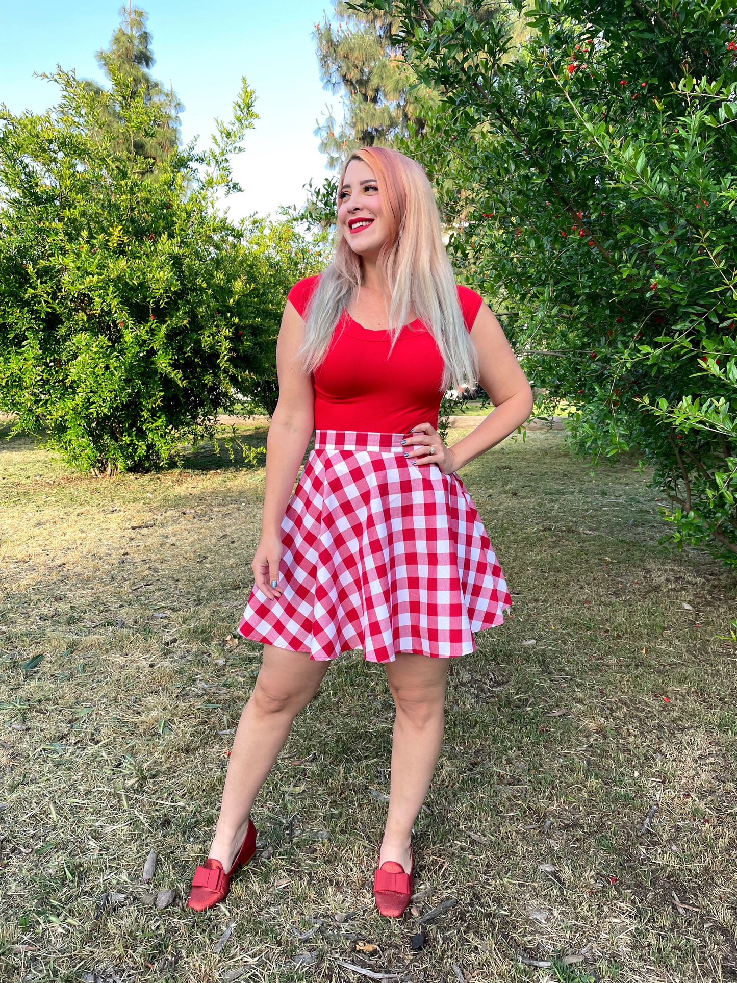 a model outdoors in front of trees wearing red gingham skater skirt