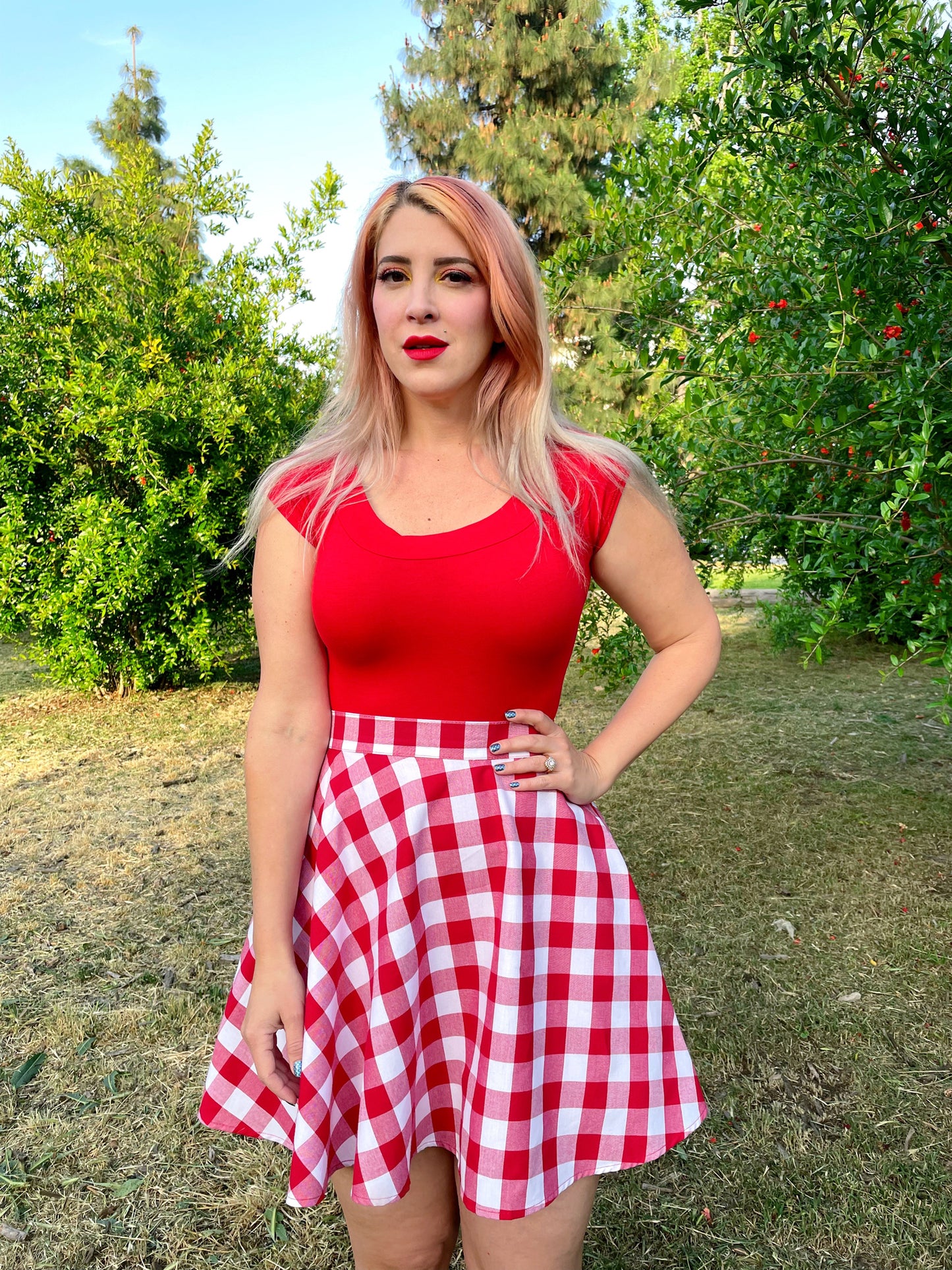 a model outdoors in front of trees wearing red gingham skater skirt