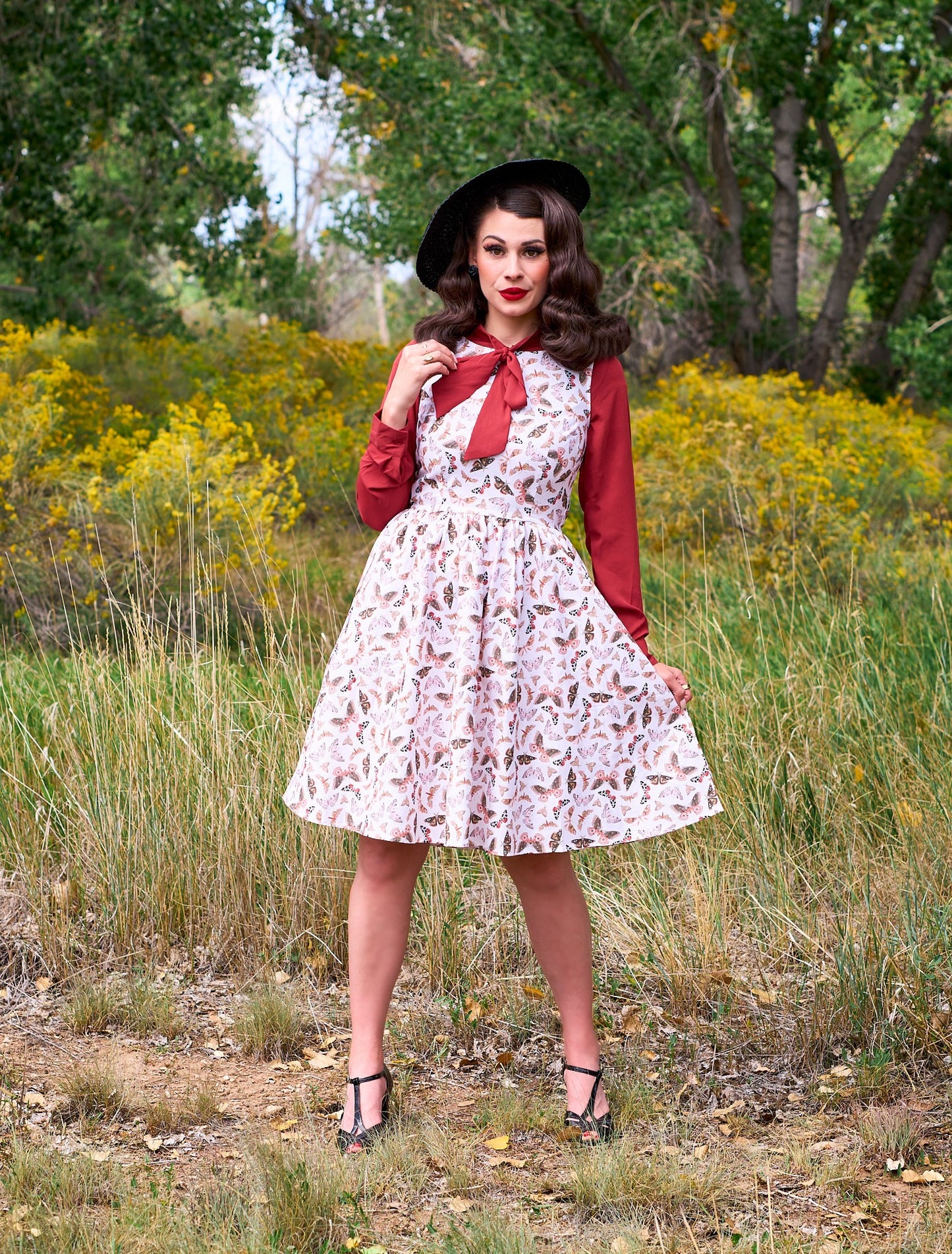 a full length of a model standing in front of trees wearing the helen retro blouse in cognac shown under a dress