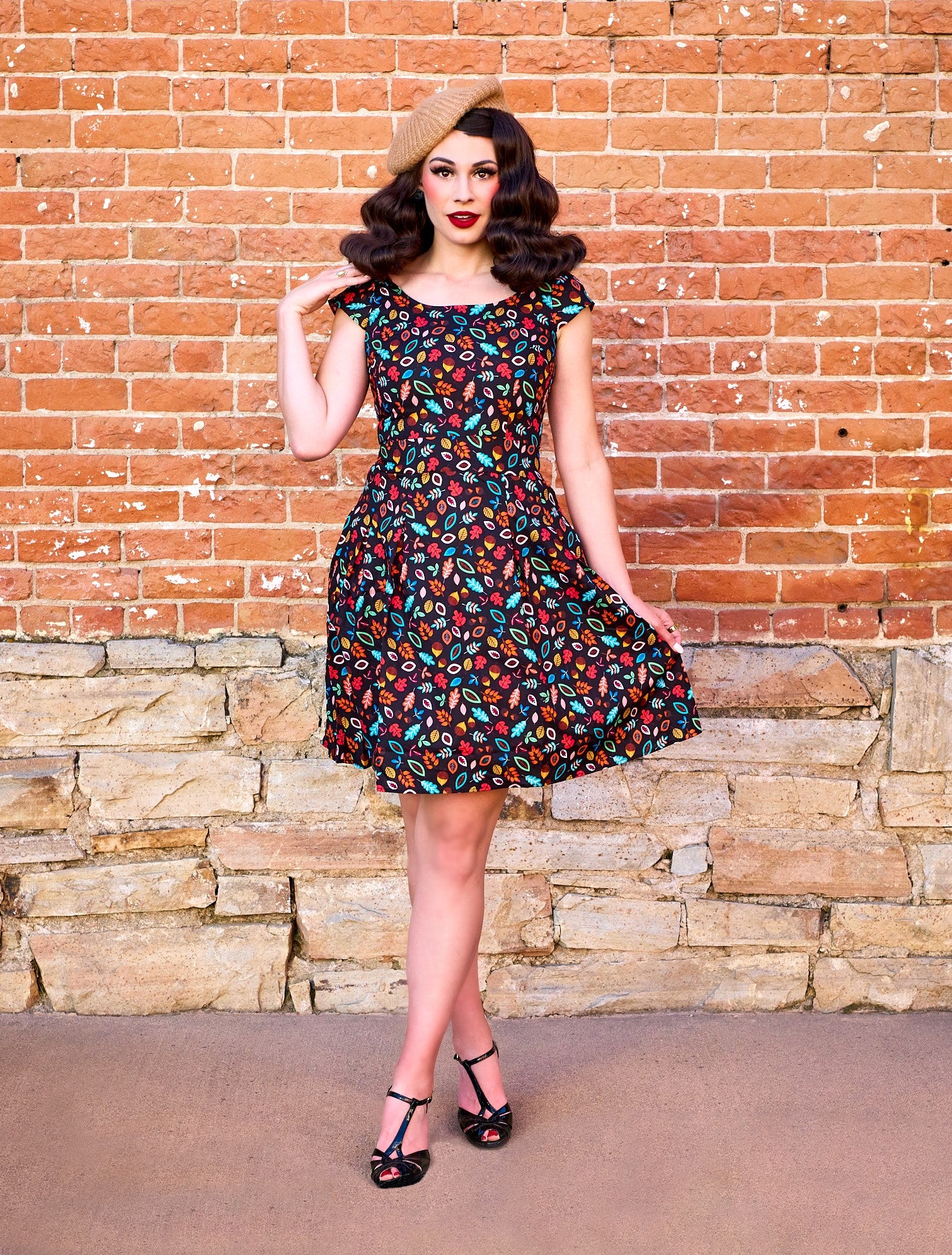 a model standing in front of brick wall wearing the leaves and acorn margaret dress and beret