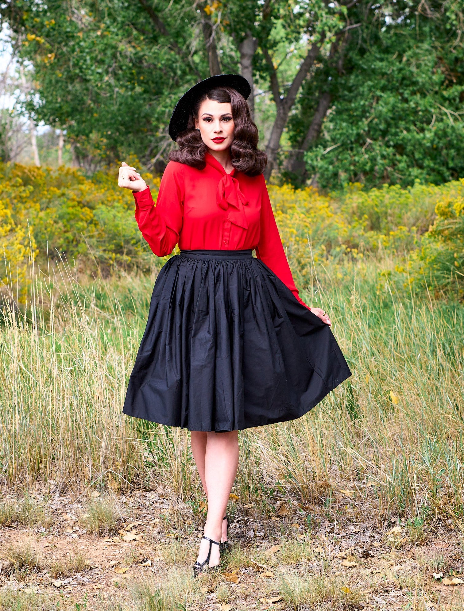 a full length of a model standing in front of trees wearing the helen retro blouse in red
