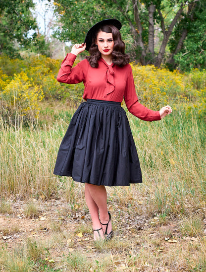 a full length of a model standing in front of trees wearing the helen retro blouse in cognac