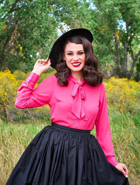 a close up of a model standing in front of trees wearing the helen retro blouse in pink