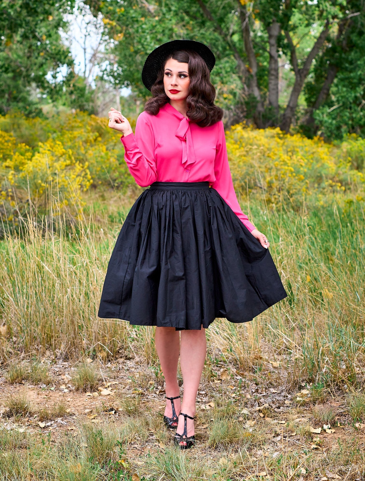 a full length of a model standing in front of trees wearing the helen retro blouse in pink
