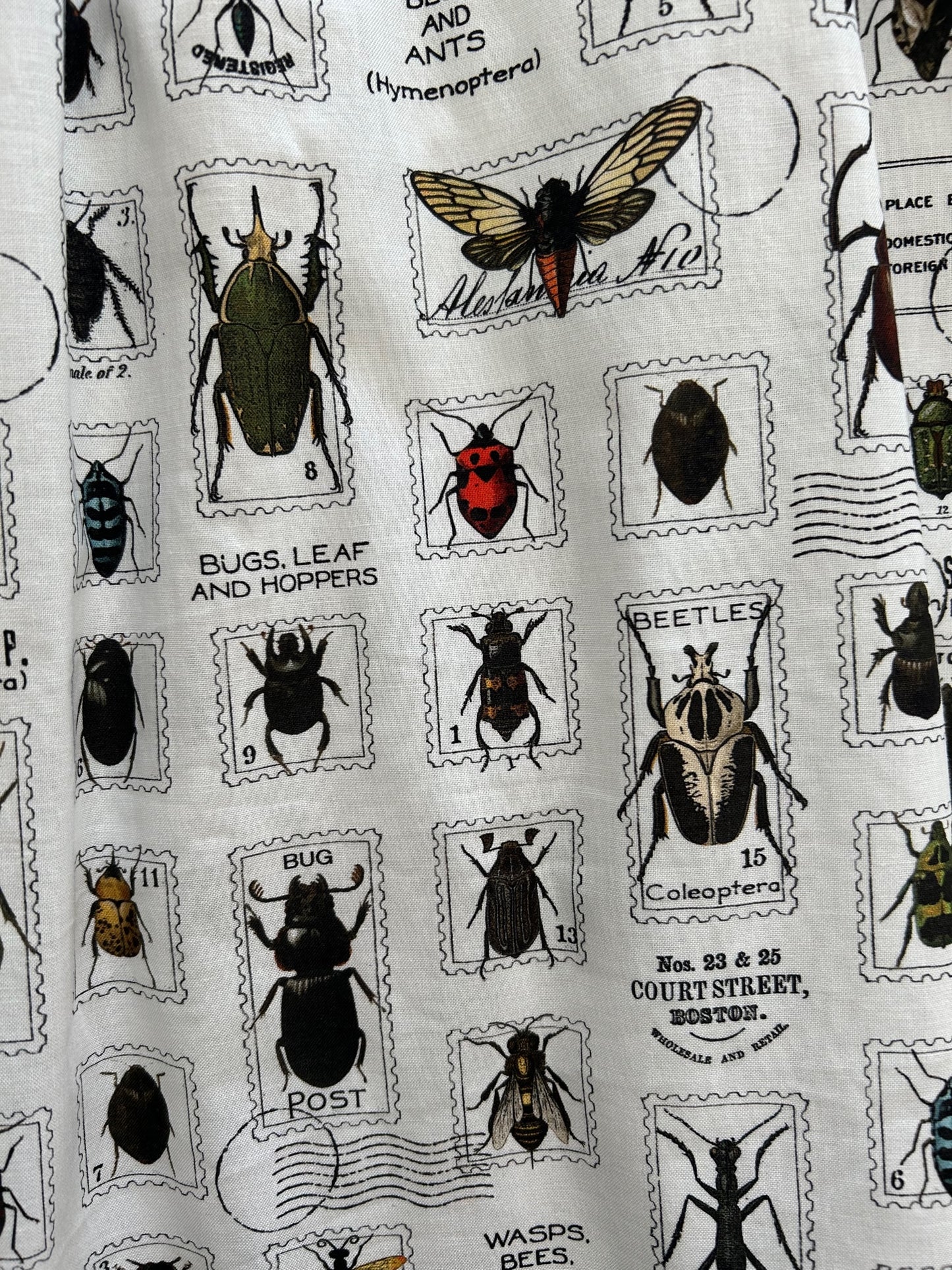 a close up of the fabric showing the stamps with different bugs on white background