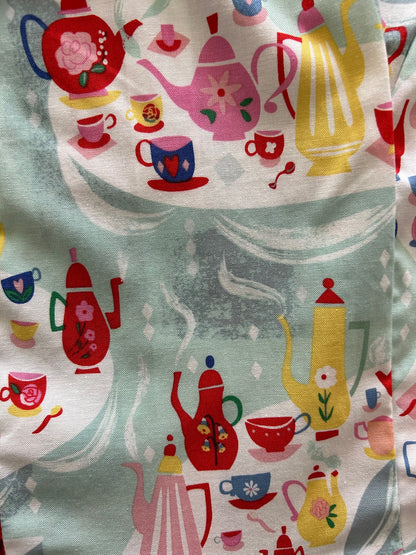 a close up of the fabric of the tea party collared dress showing tea cups and tea pots