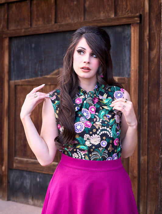 a close up image of model standing in front of a wooden wall and wearing the hummingbird bow top