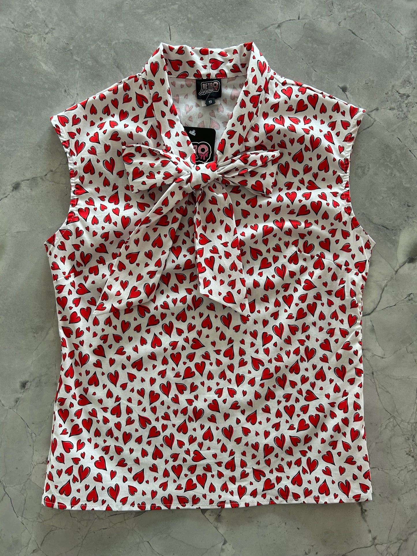 a flat lay of our sleeveless bow tie blouse with hearts fabric