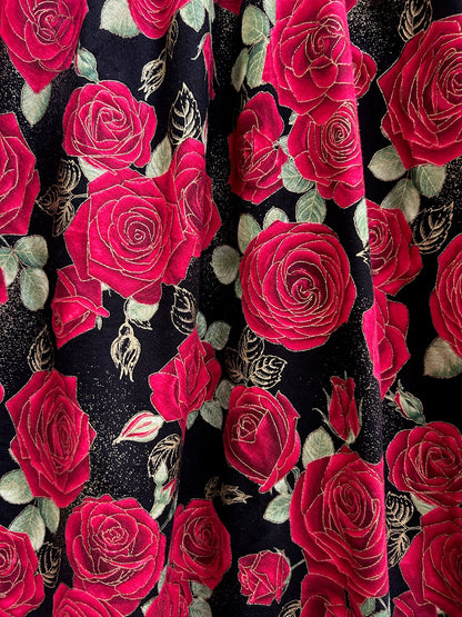 a close up of the fabric showing the red roses on black background and the gold metallic accents