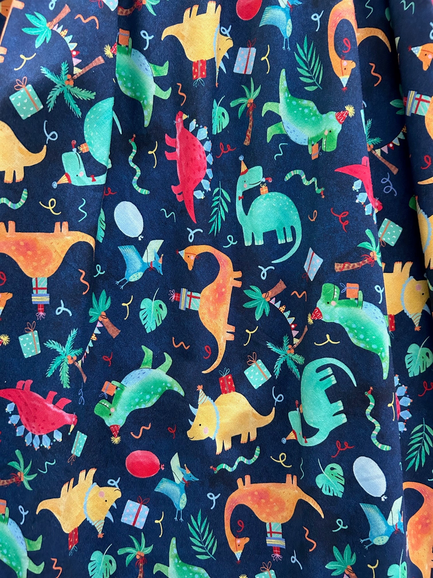 a close up of the fabric showing dinosaurs in party hats and gifts