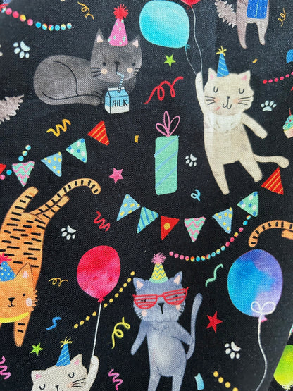 a close up of the fabric of the front of the party cats skater skirt showing cats in party hats with balloons and festive decorations