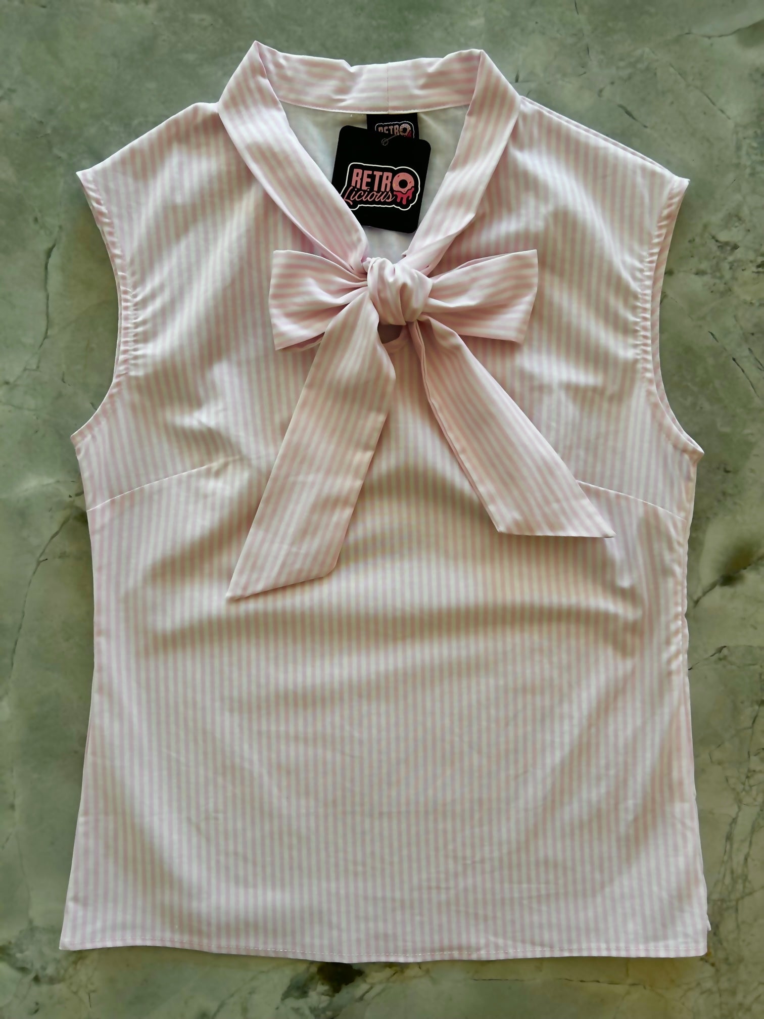 a flat lay of our bow tie blouse with pink and white vertical stripes