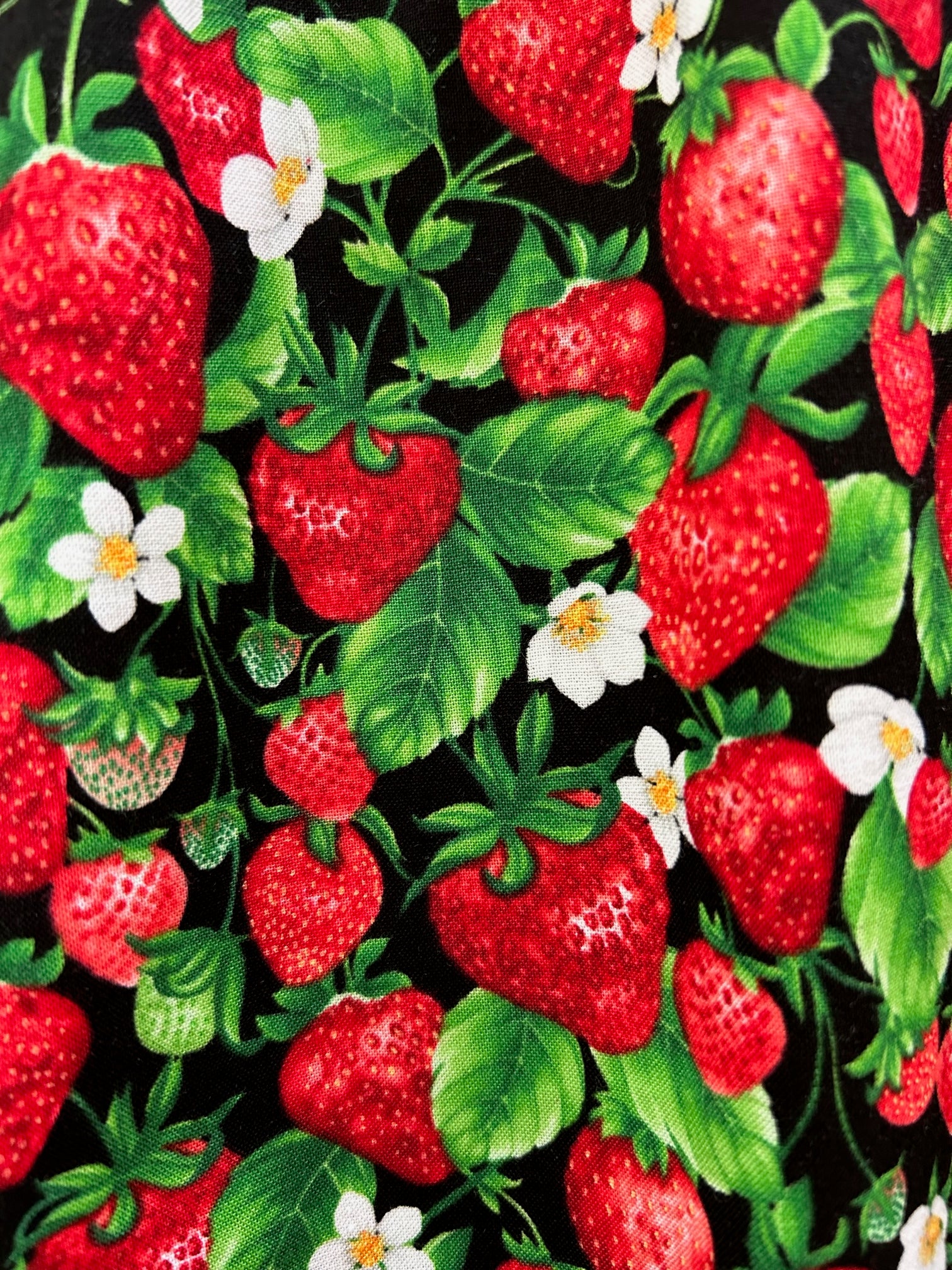 a close up of fabric showing strawberries and blossoms on black background