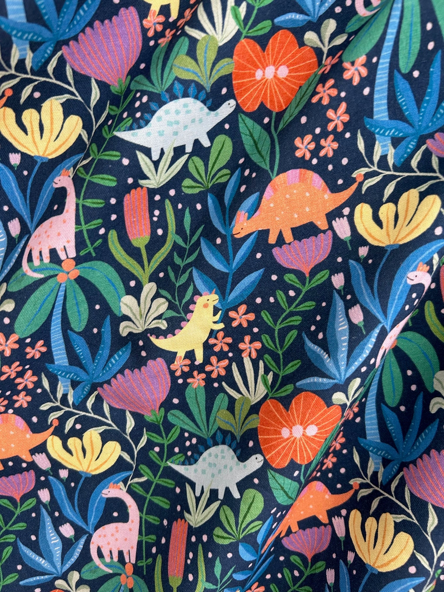 a close up of the fabric of the prehistoric vintage dress showing colorful dinosaurs on plants