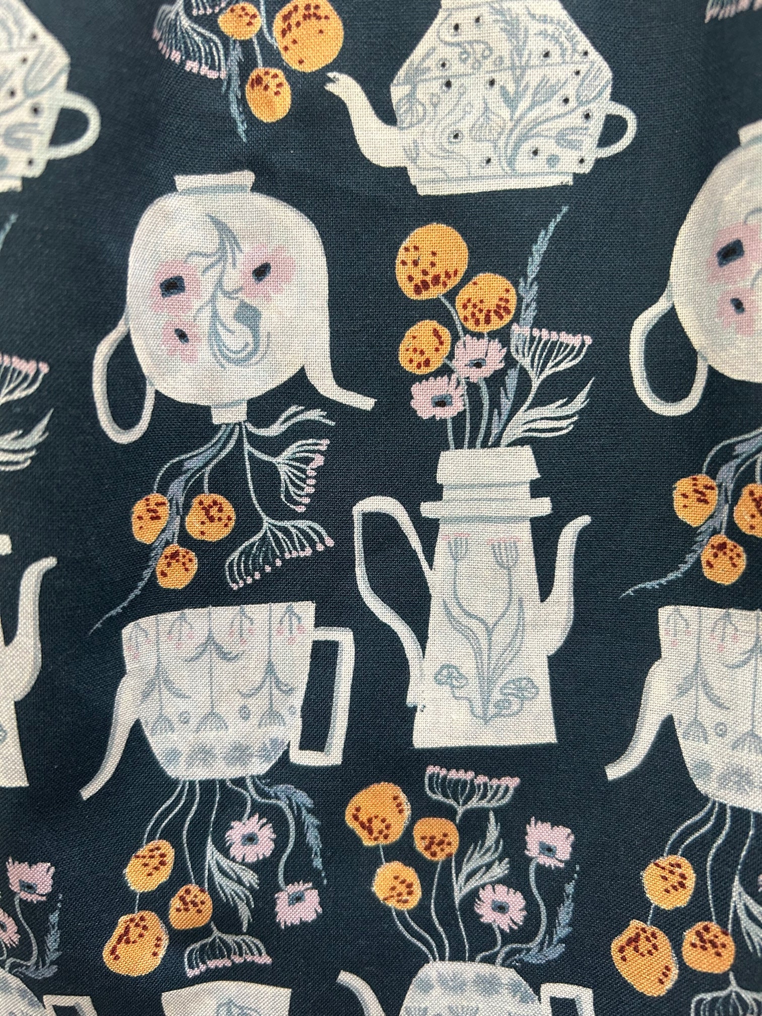 a close up of the fabric of teapots fit and flare dress showing teapots with flowers in them on navy blue background