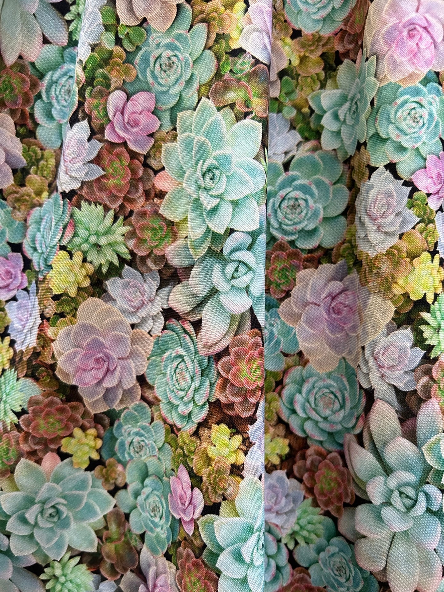 a close up of the fabric showing tightly packed succulents in pastel colors