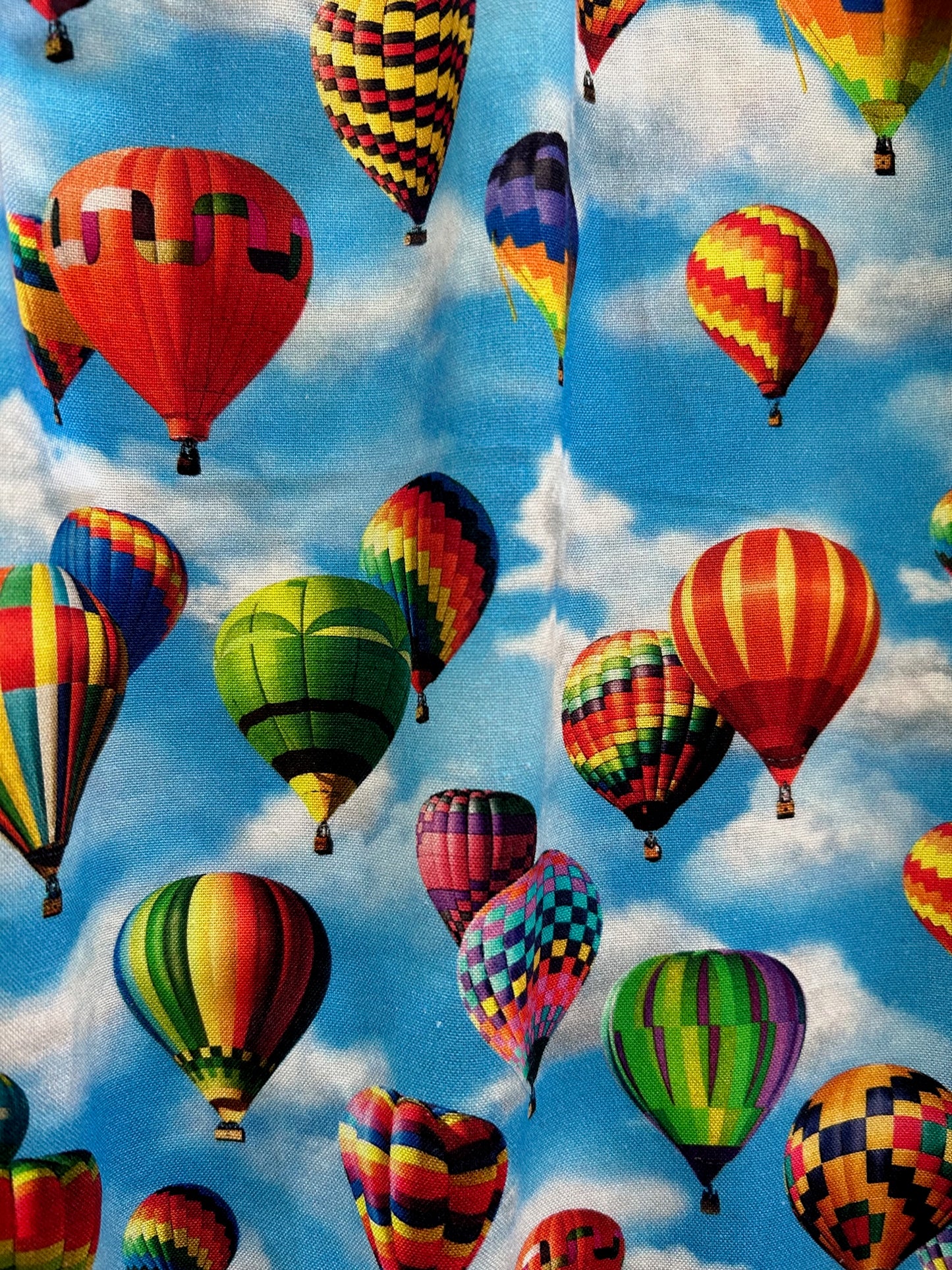 a close up of the fabric showing colorful hot air balloons on a background on blue skies and white clouds