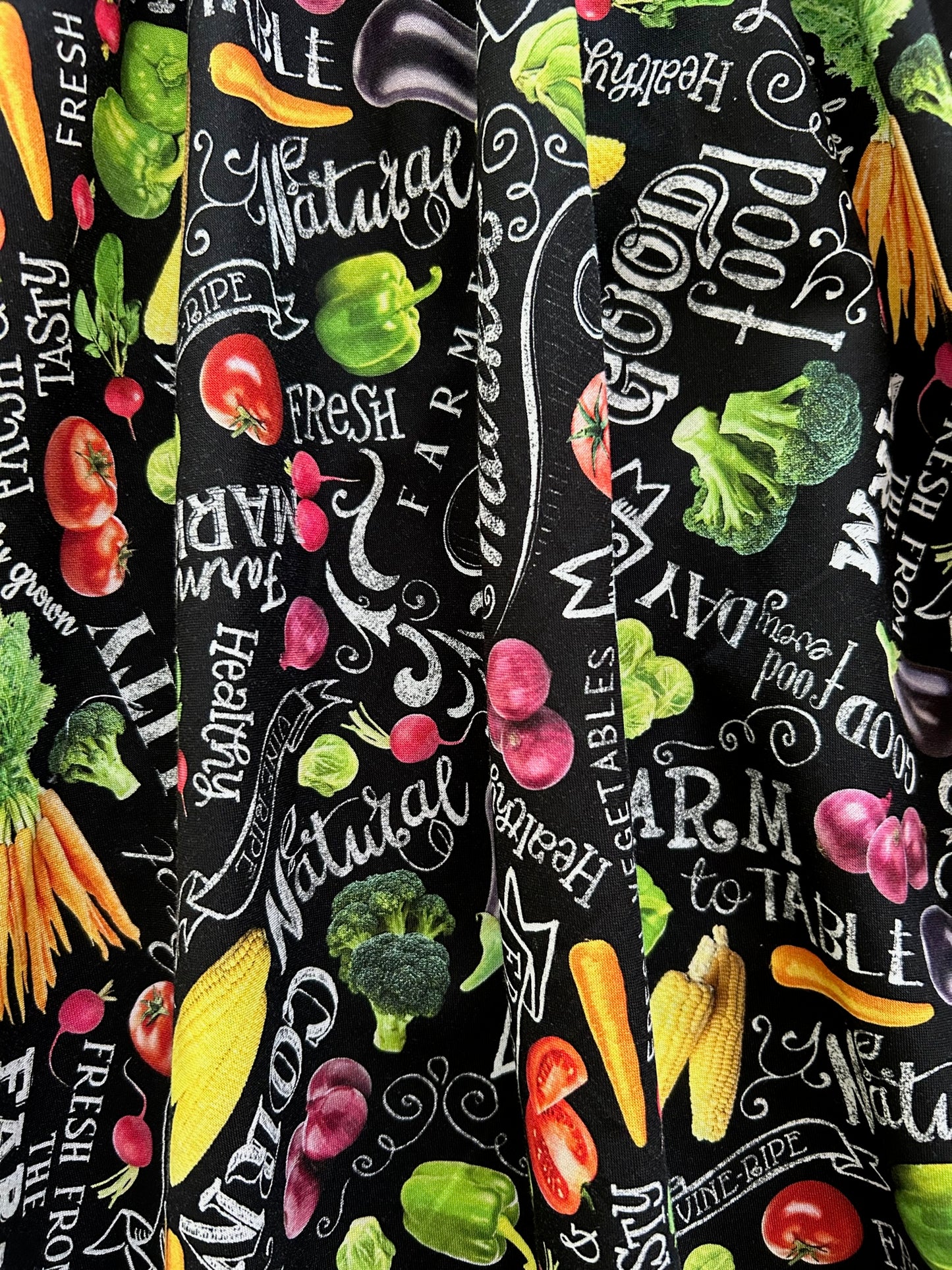 a close up of the fabric of the farm fresh vintage dress showing he chalkboard style writing and tossed fruits and veggies all over