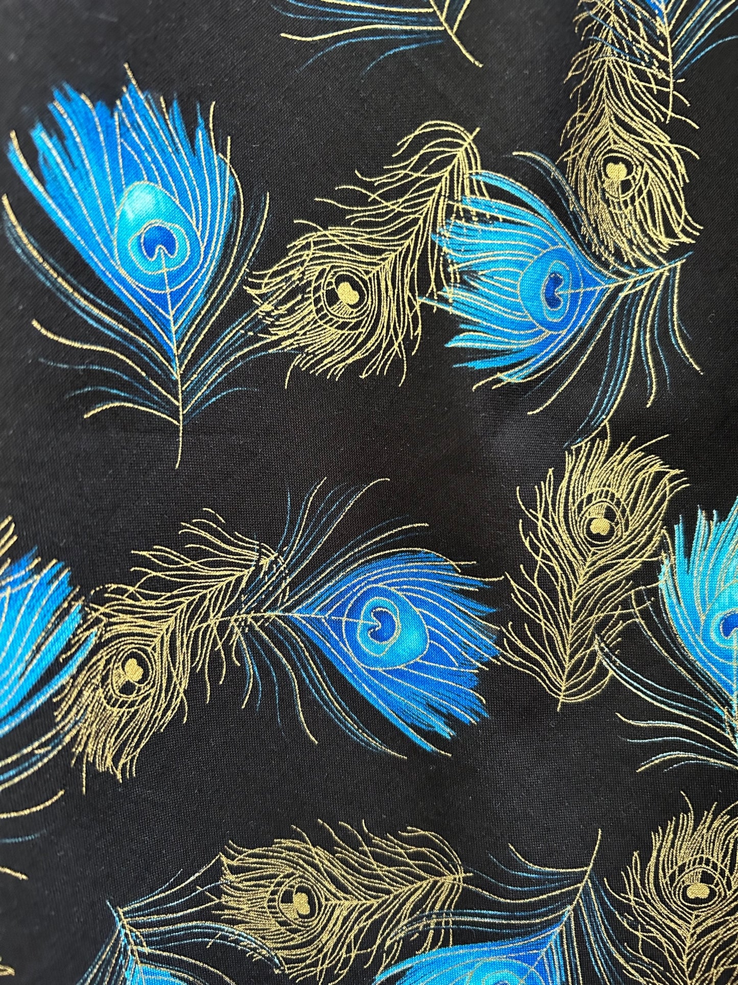 a close up of the fabric showing gold and blue peacock feathers