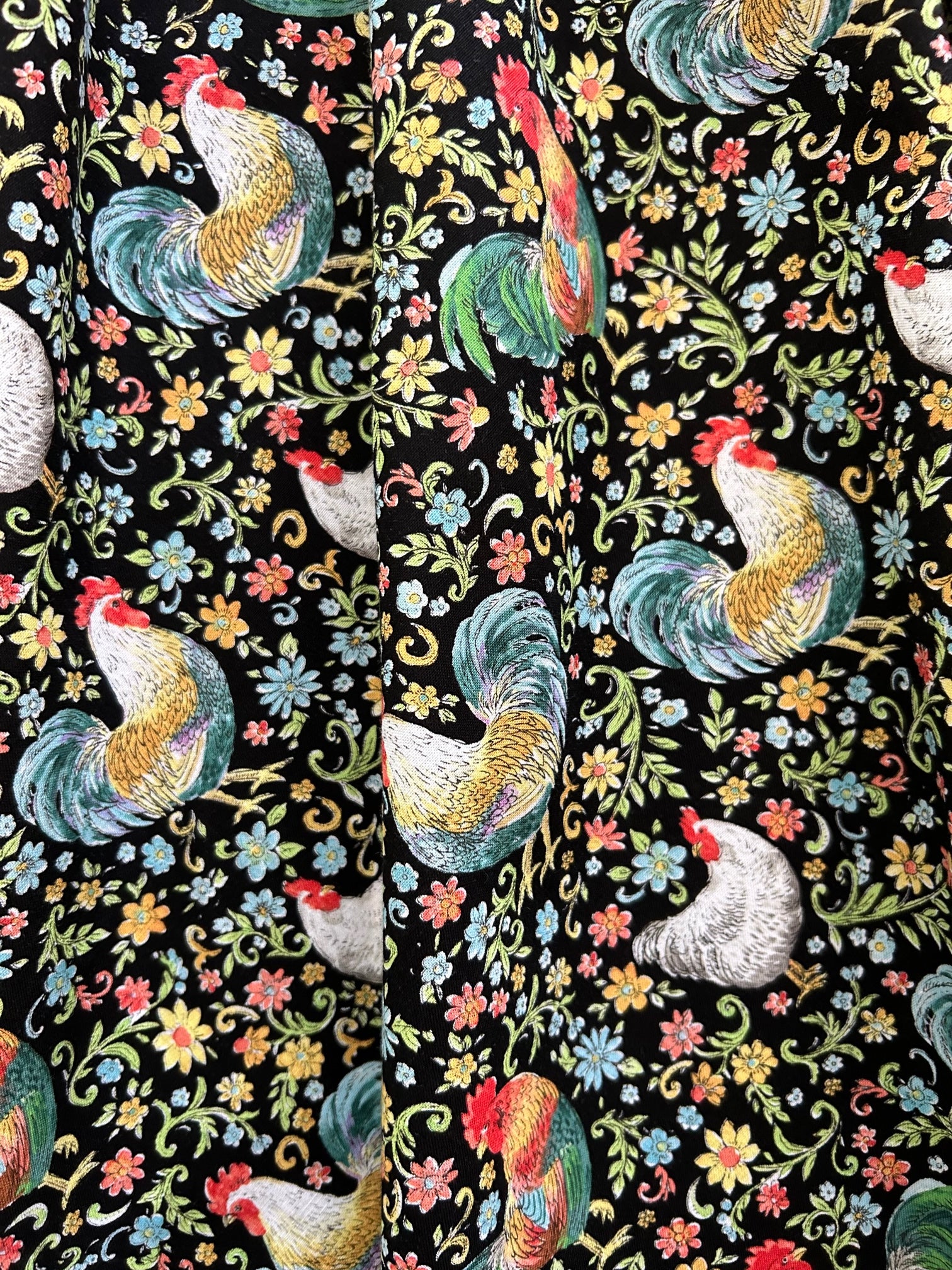 a close up of the fabric showing the chickens and roosters on a floral background