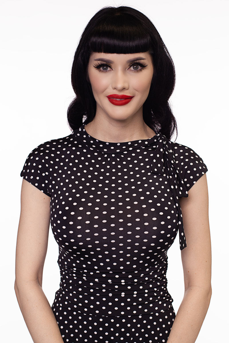 a close up image of a model wearing the bridget bomshell dress in black and white polka dots