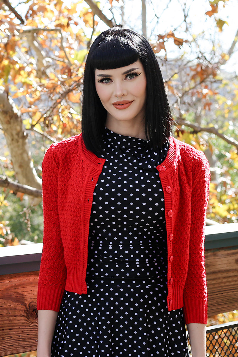 Model wearing red waffle cardigan open over polka dot dress