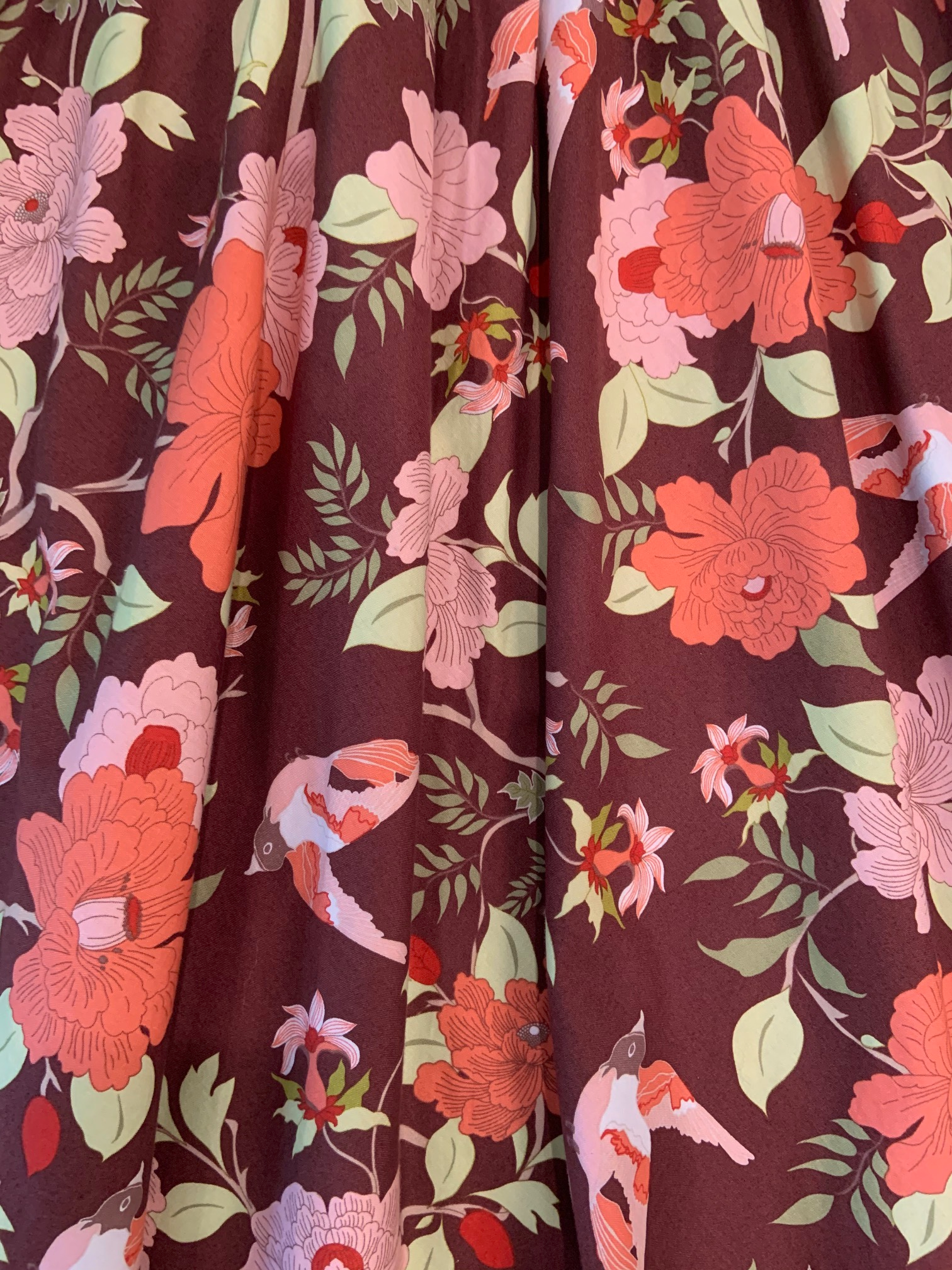a close up of the floral print with orange and pink flower on brown base