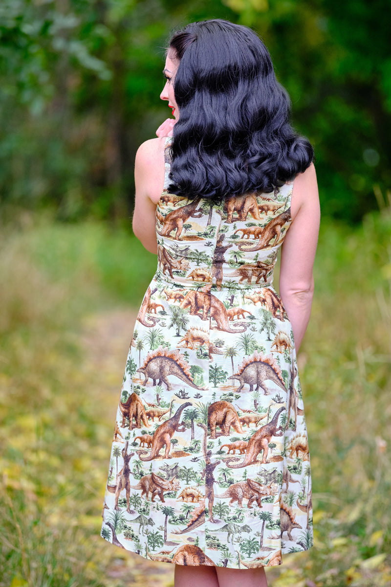 a backshot of a  model standing in front of trees wearing the prehistoric dress the background is blurred