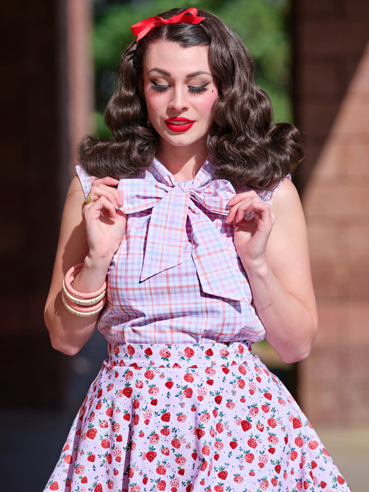 a close up of a model wearing our sleeveless bow tie blouse with plaid fabric